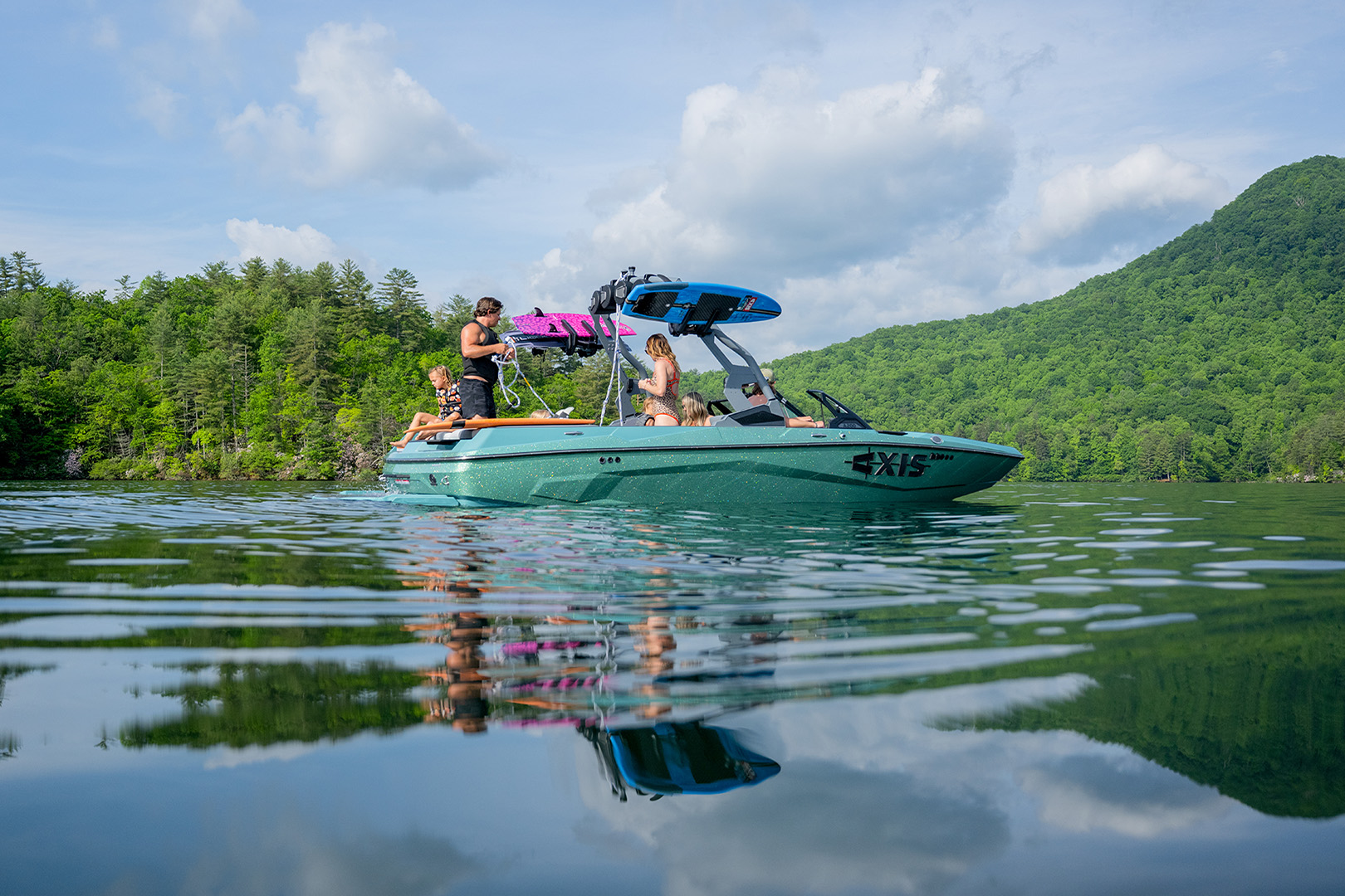 Family relaxes on the Axis A200 floating in a peaceful lake surrounded by trees.