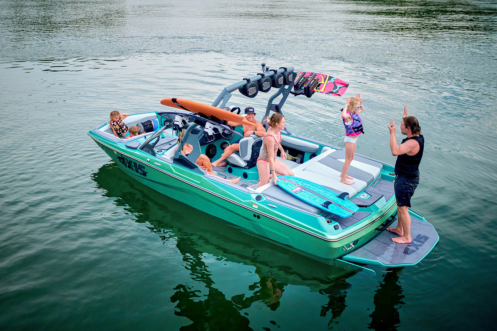 A family gathers on the Axis A200’s swim platform with gear and towels in hand, ready for a day of surfing and fun.