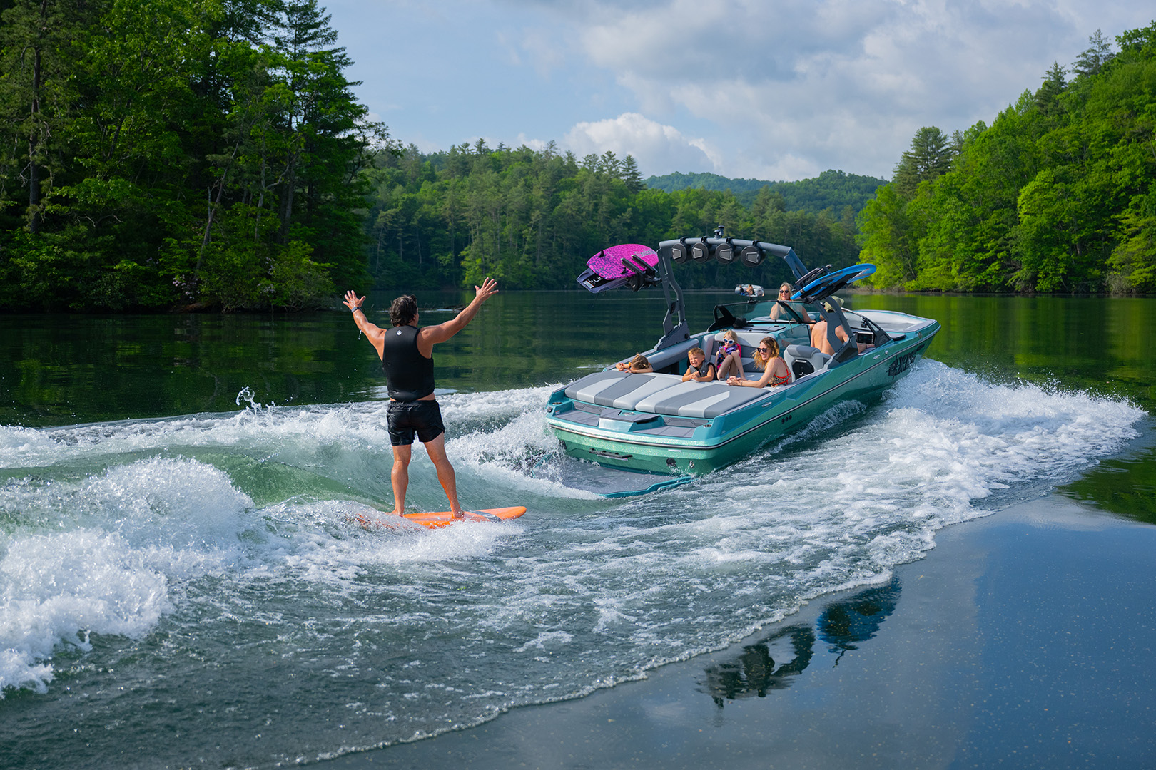Female rider carves on a wakesurf wave behind an Axis wakeboat, showing the clean wave shape created by Surf Gate®.