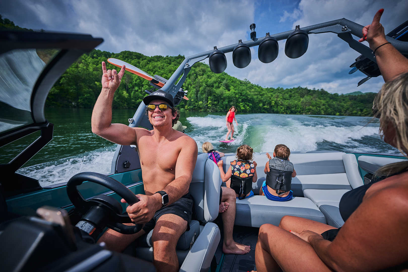 Family and rider inside the Axis A200 watching a wakesurfer, highlighting the seating layout and tower speakers.