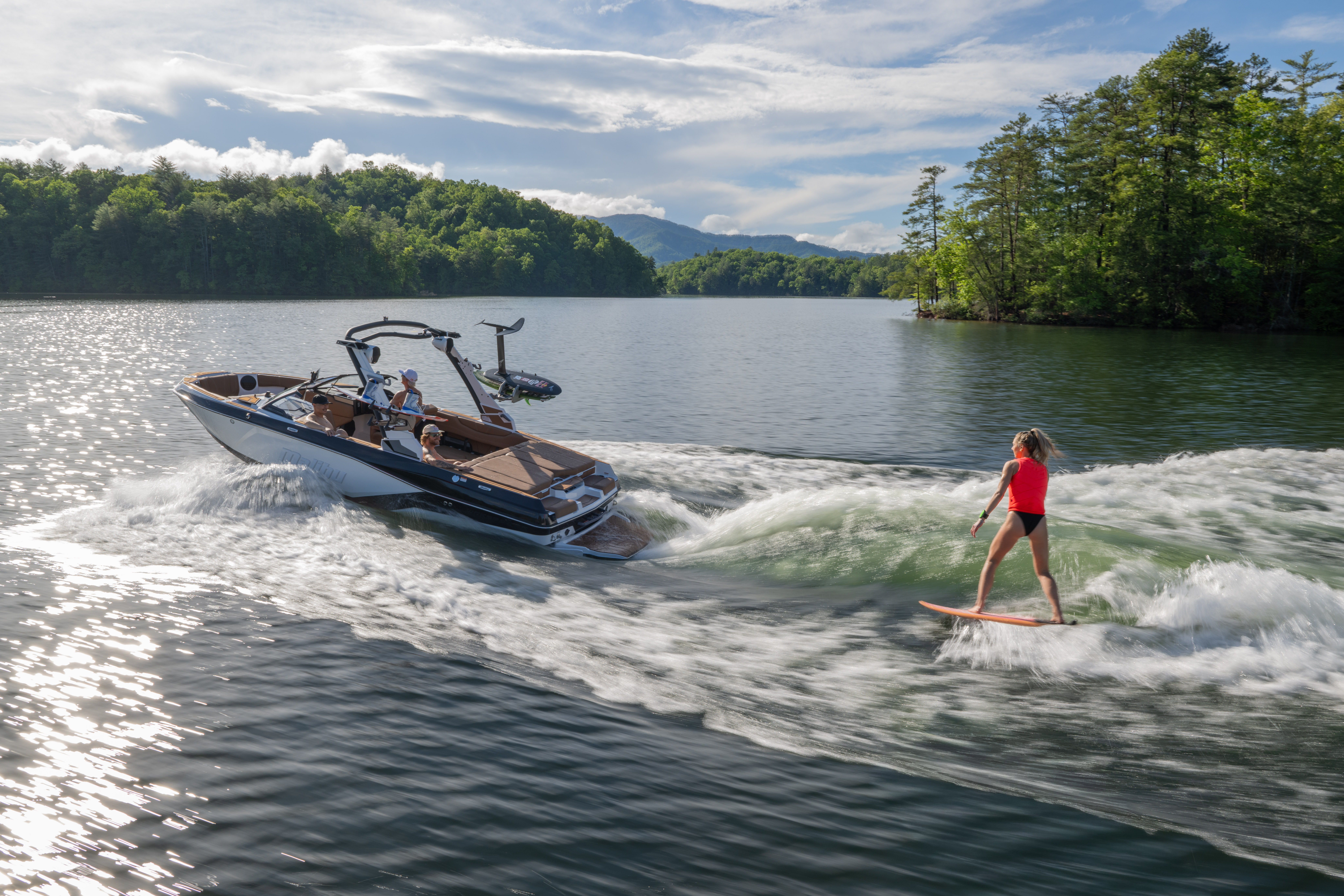 Surfer rides a clean wave behind a Malibu 21 LX with powerful curl.