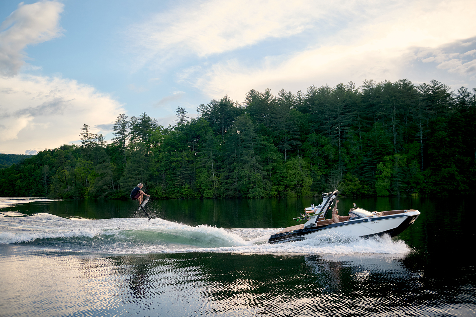 Wakeboarder launches off the wake behind the 21 LX with sunset lighting.