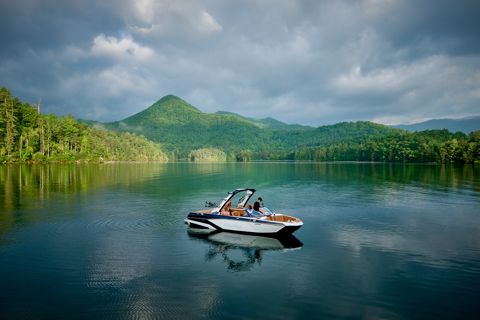 Malibu 21 LX floats on a calm lake, highlighting the Hybrid Bow and sleek profile.