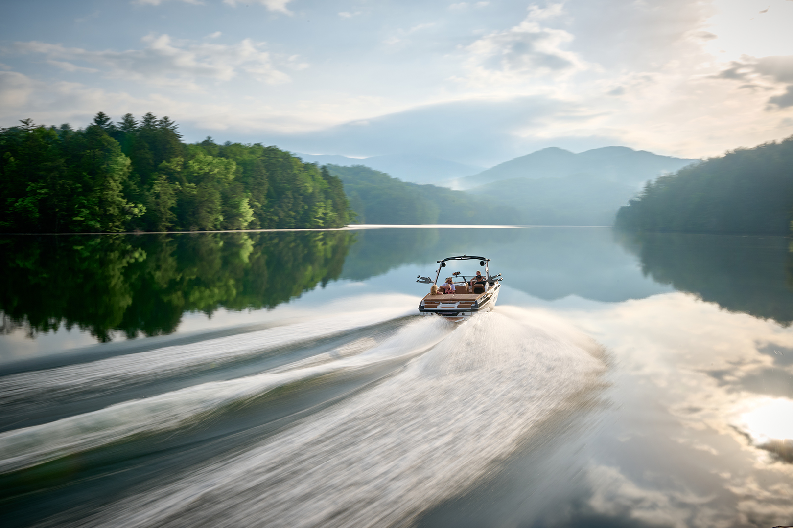 The 2026 Malibu Wakesetter 21 LX creates a clean, well-formed wake as it pulls away from the camera on a scenic lake.