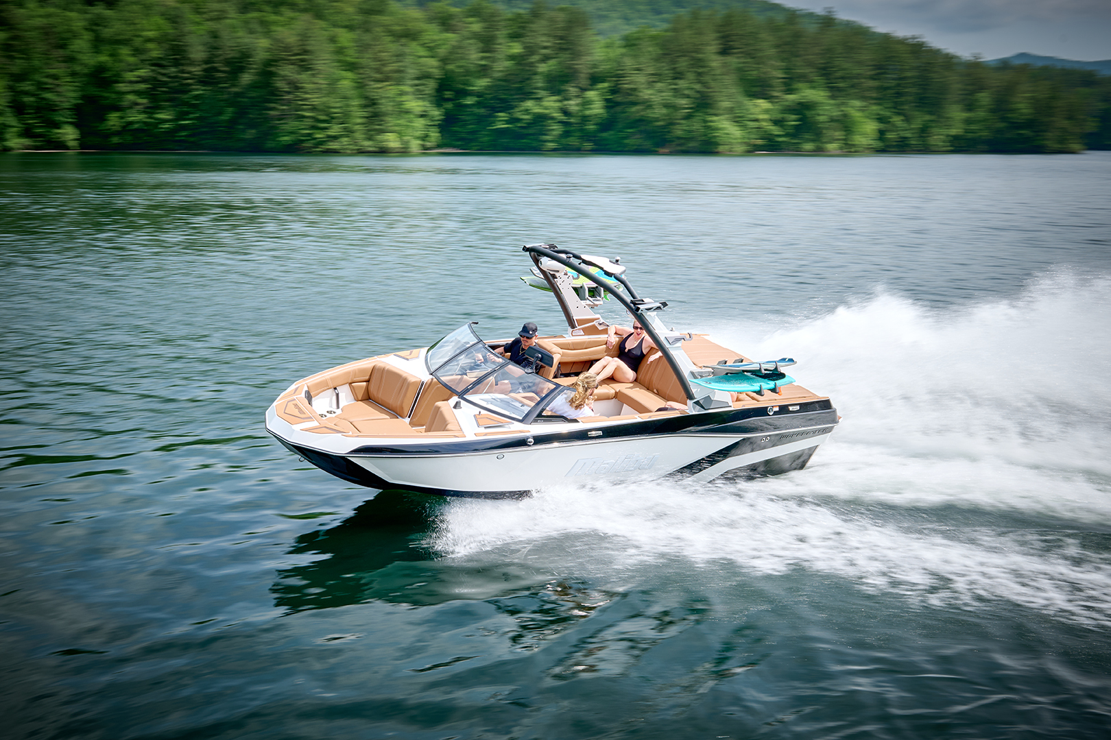 2026 Malibu 21 LX speeds across the water with bow seating and tower speakers in view.