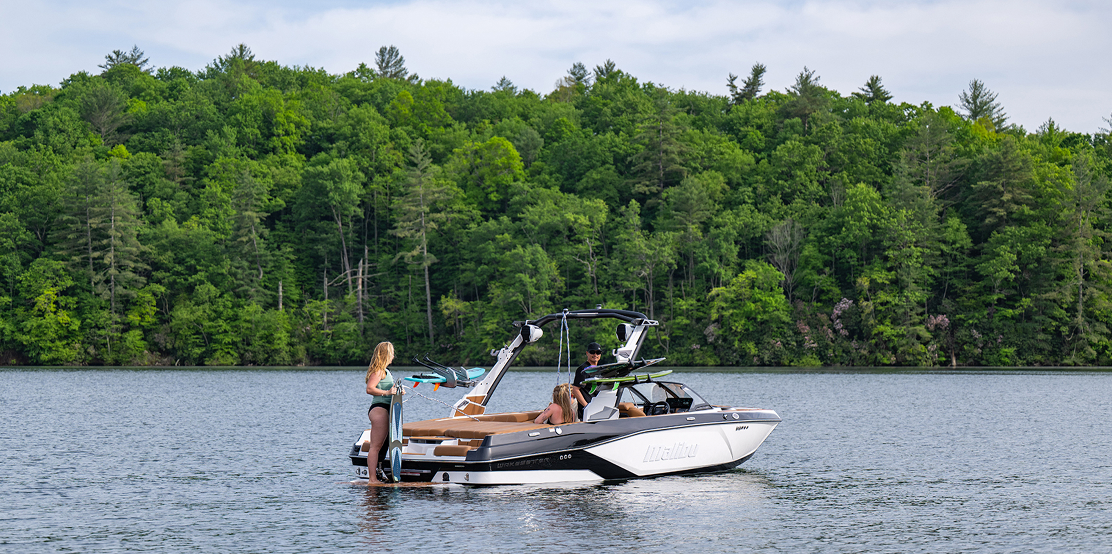 People relax on the swim platform of a 2026 Malibu 21 LX, showcasing rear access and lounging space.